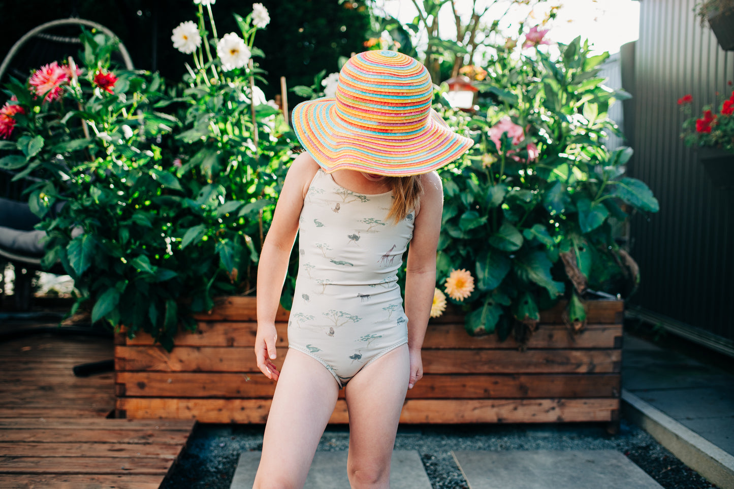 Person wearing a patterned swimsuit and colorful hat in a garden setting