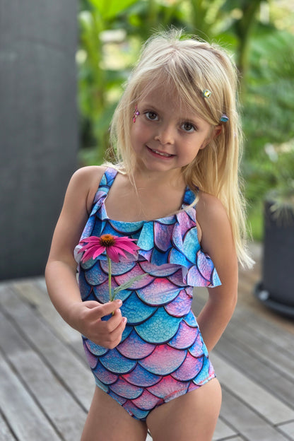 Child wearing a colorful mermaid-themed dress outdoors
