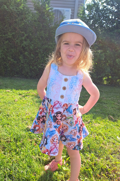 Child wearing a dress with cartoon characters outdoors on grass