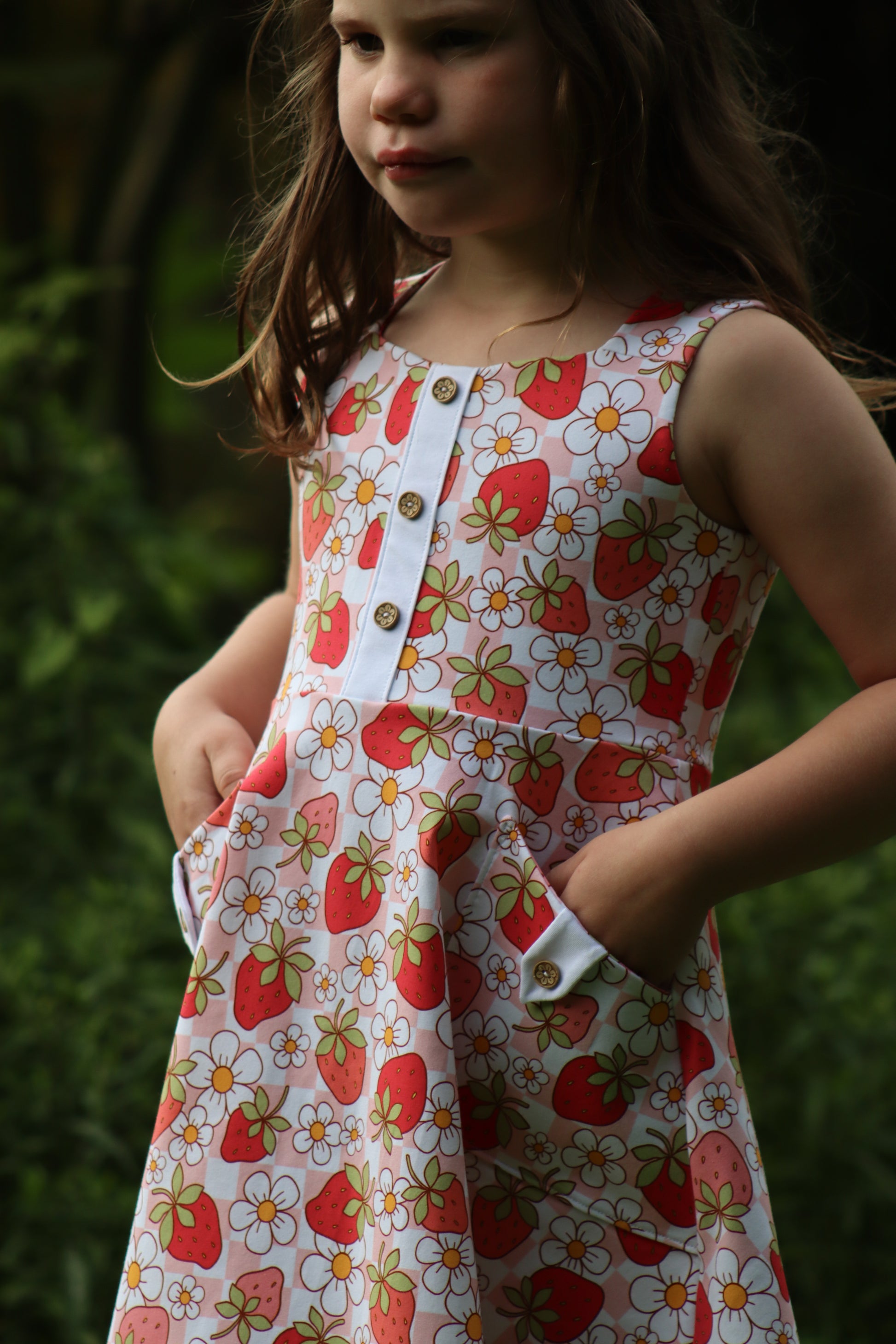 Young girl wearing a dress with strawberry pattern and pockets