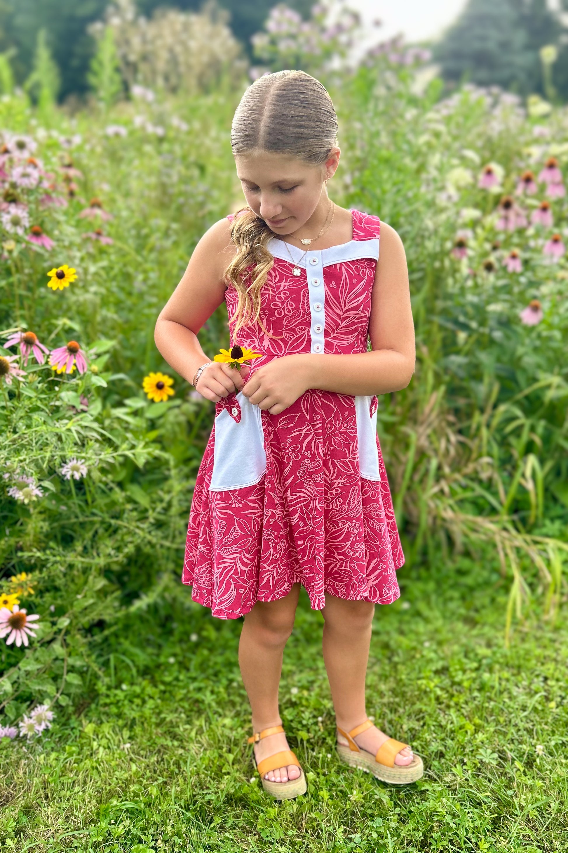 Young girl in a pink dress standing in a field of flowers