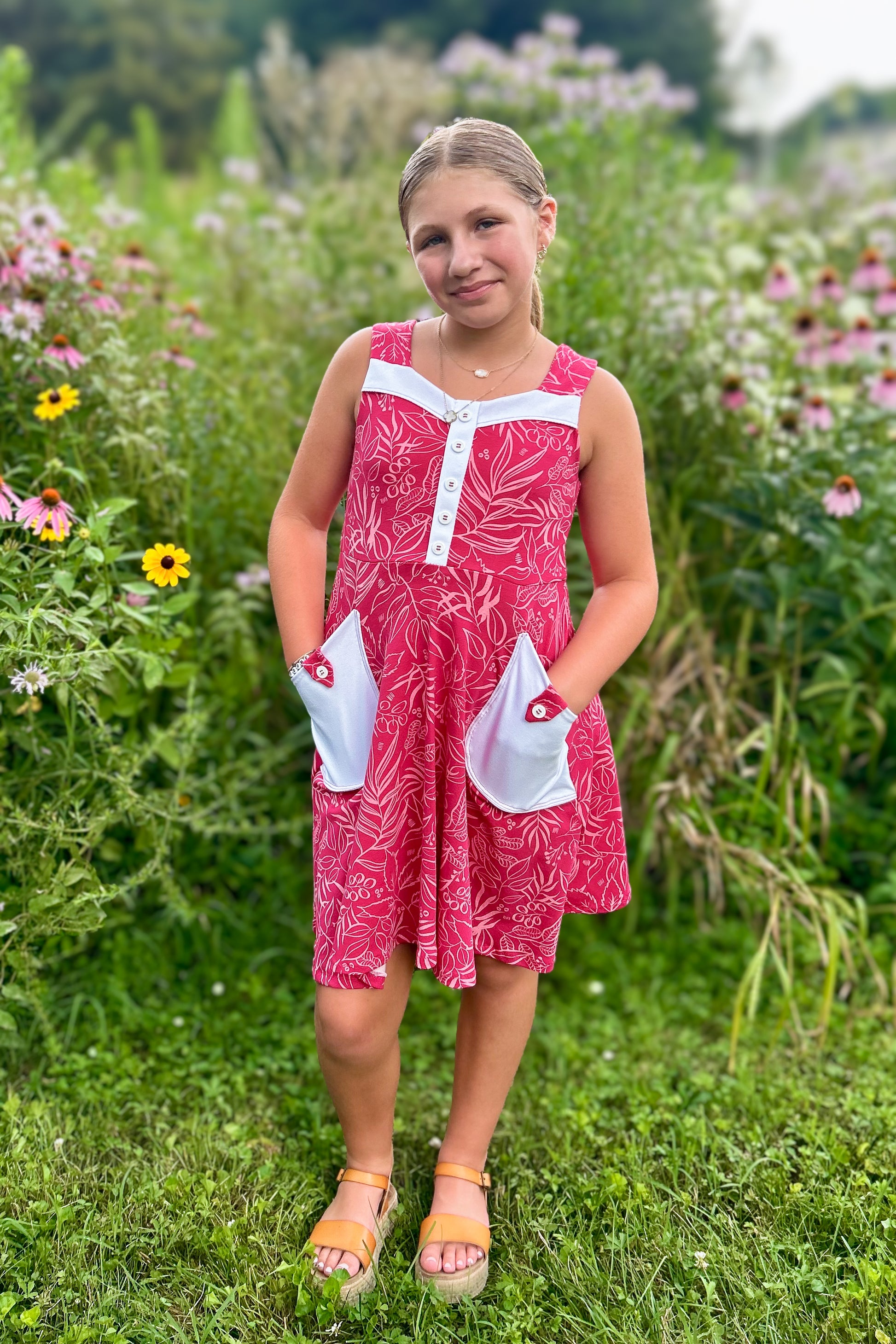 Young girl in a pink dress standing in a field of flowers